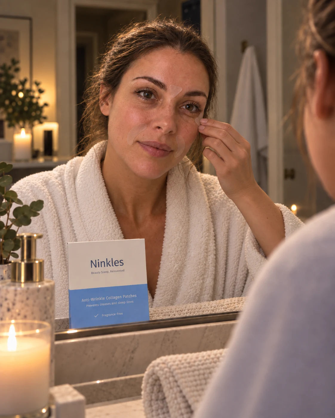 A woman applying a patch at the mirror as part of her nighttime routine, with the Ninkles patch box visible on the counter.