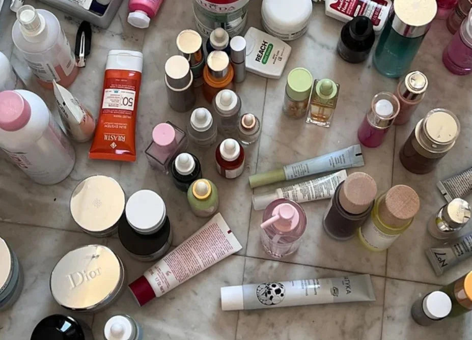 A messy counter covered in serums, creams and skincare bottles.